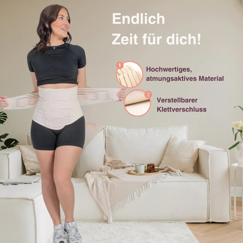 Frau mit Bauchgurt nach der Geburt im Wohnzimmer – zeigt den Gurt im Alltag.